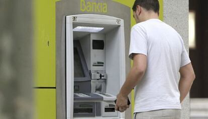 Un hombre saca dinero de un cajero automático de Bankia.