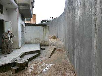 Una mujer palestina observa desde la puerta de su casa el muro construido por Israel.