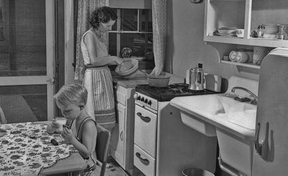 Una mujer prepara la comida en la cocina junto a su hijo.