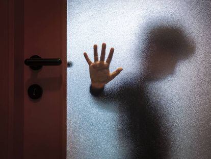 Una persona apoya su mano contra el cristal de la puerta de una consulta médica.