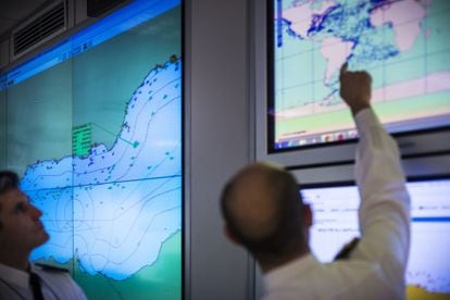 A la izquierda, el capitán de fragata Sebastián Bienert, jefe de operaciones y de Inteligencia del COVAM. Detrás de él, un mapa que muestra los tráficos e incidentes en el Estrecho de Gibraltar. A la derecha, otro mapa relaciona los tráficos mundiales con el Estrecho.