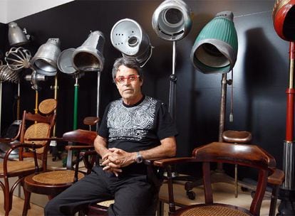 Raffel Pages sentado junto a algunos de los secadores de casco eléctricos de su colección.