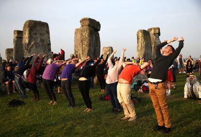 Varias personas practican yoga en el monumento Stonehenge.