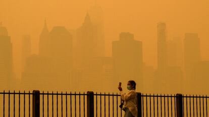 Una mujer con mascarilla fotografía el cielo de Nueva York.