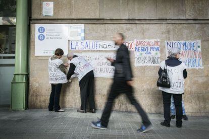 Miembros de Tancada Clínic pegan carteles contra la privatización en la fachada del centro público.
