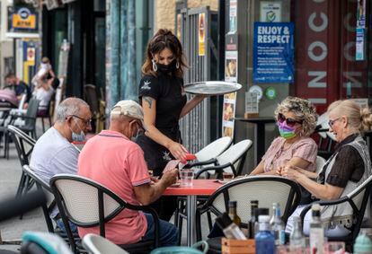 Una camarera sirve una mesa en una terraza de Benidorm.