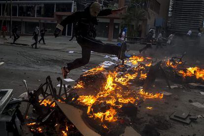 Un manifestante salta una barricada con fuego durante enfrentamientos con integrantes de la Policía Nacional Bolivariana en una protesta contra el gobierno del presidente venezolano Nicolás Maduro, 12 de marzo del 2014, en la plaza Altamira en Caracas (Venezuela).