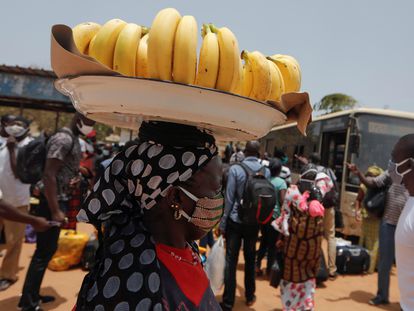 Una vendedora callejera carga con una cesta de plátanos sobre su cabeza por una concurrida calle de Dakar, capital senegalesa, en mayo de 2020.