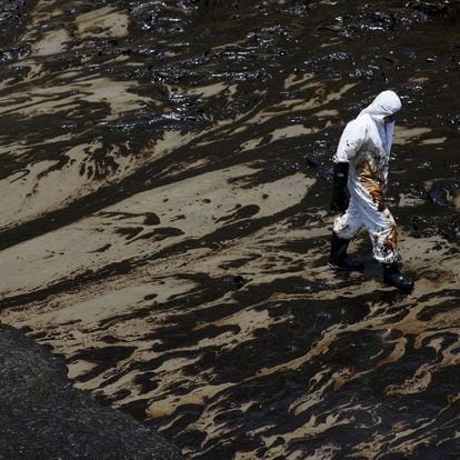 A worker walks following an oil spill caused by abnormal waves, triggered by a massive underwater volcanic eruption half a world away in Tonga, at the Peruvian beach in Ventanilla, Peru, January 18, 2022. REUTERS/Pilar Olivares