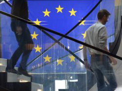 Dos hombres bajan por una escalera delante de una bandera de la Uni&oacute;n Europea, durante una sesi&oacute;n plenaria en el Parlamento en Estrasburgo.