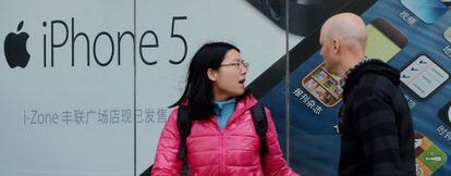 Una pareja camina por delante de una tienda de Apple en Pek&iacute;n (China)