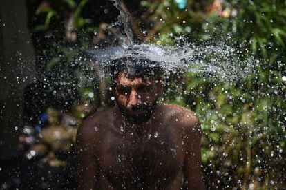 Un paquistaní se baña bajo un chorro de agua en Islamabad (Pakistán).