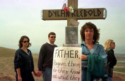 Gente visitando la zona donde se levantó un homenaje a las víctimas de la masacre de Columbine, en Littleton, Colorado. En la imagen, una cruz con la foto y el nombre de Dylan Klebold y una pancarta donde se lee: "Señor, perdónalos porque no saben lo que hacen" (Jesus).