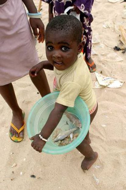 Una niña nigeriana porta un recipiente de plástico con unos peces en su interior en el enclave pesquero de Agodo, cerca de Lagos (suroeste de Nigeria). EFE/Archivo