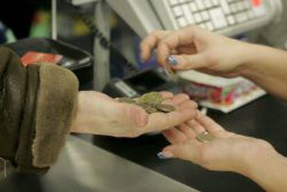 Una cajera ayuda a un cliente a contar las monedas de euro. EFE/Archivo