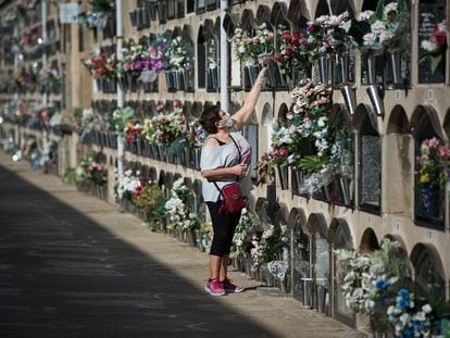 Una mujer deposita flores en un nicho del cementerio del Poblenou de Barcelona.