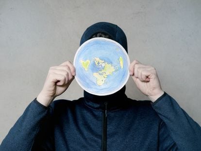 Un hombre sostiene un dibujo del planeta Tierra según los terraplanistas.