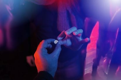 Una persona entrega una pastilla de MDMA a otra durante una fiesta.