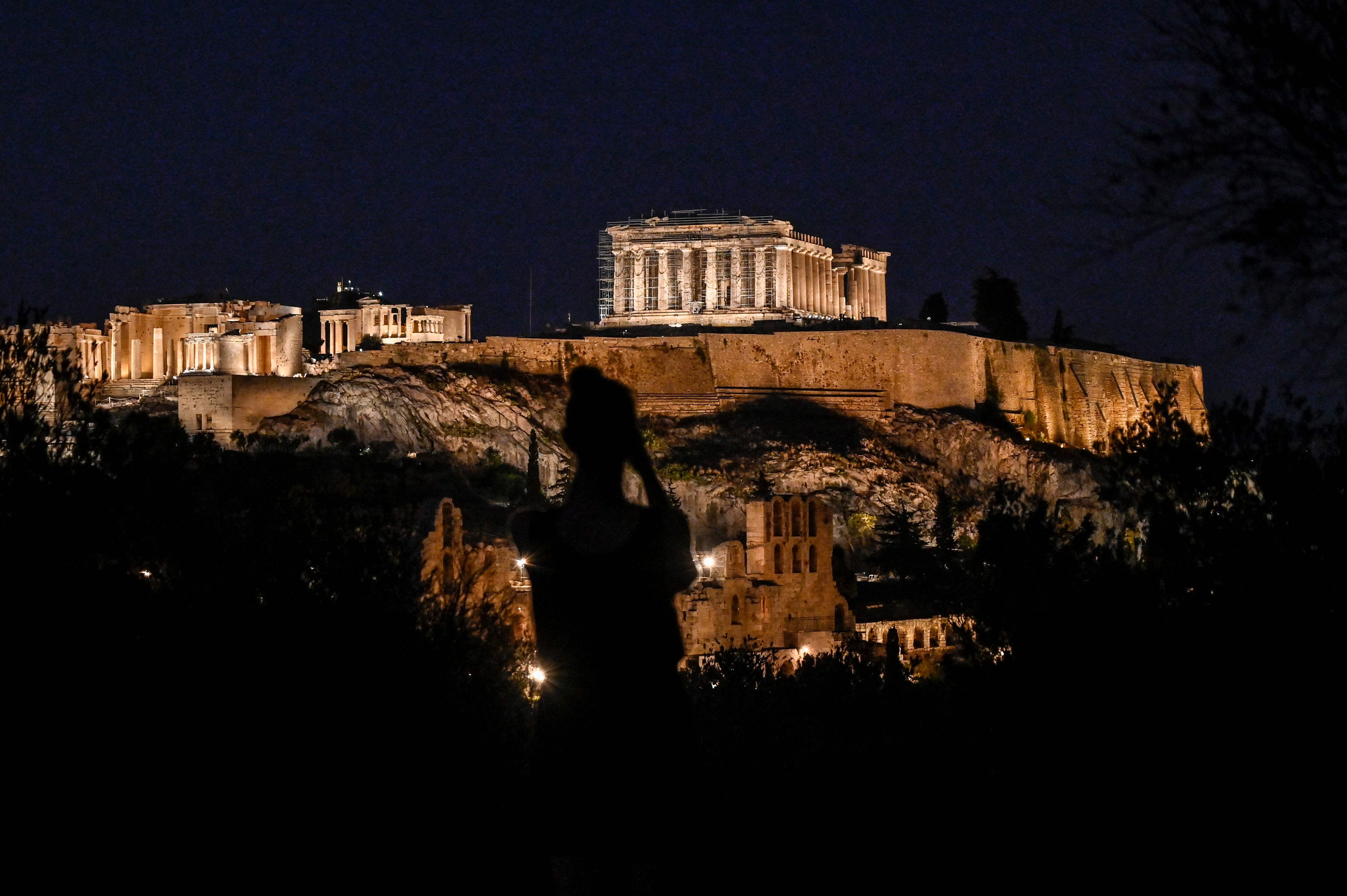 Una mujer tomaba una imagen de la Acrópolis de Atenas, iluminada, el 1 de agosto. 