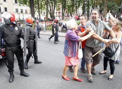 Dos mujeres sujetan a un manifestante provisto de un bastón en la marcha ilegal de Bilbao.