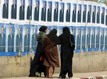 Tres mujeres argelinas caminan por una calle de Argel, junto a un muro con carteles de la campaña electoral del actual presidente argelino, Abdelaziz Bouteflika.