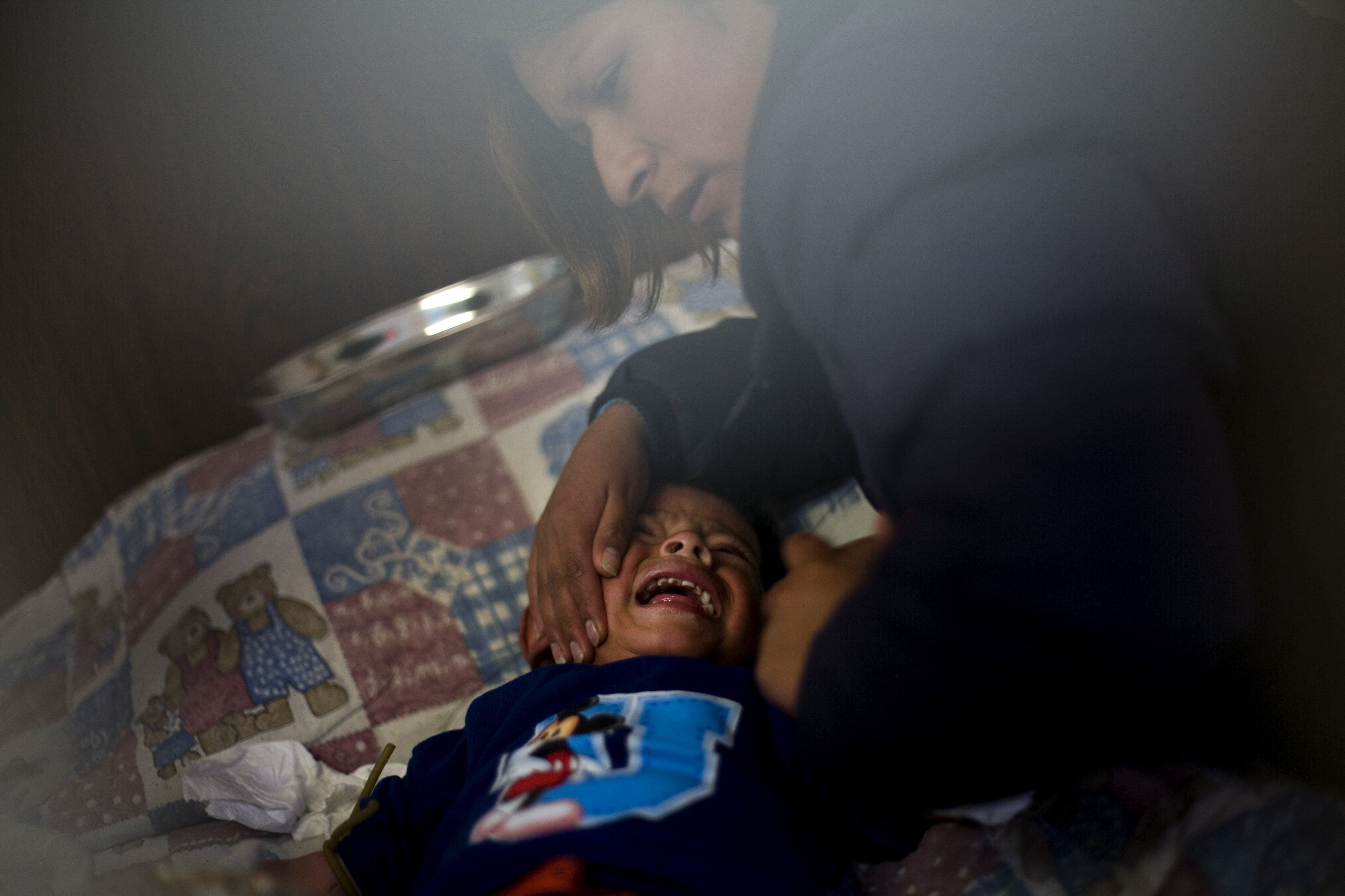 Una madre calma a su hijo mientras el Ministerio de Salud le extrae sangre para analizar el nivel de plomo en la sangre.