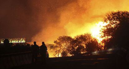 Dos policías cortan un puente amenazado por las llamas del incendio forestal que se mantiene activo en la sierra del Arca, en Cádiz.
