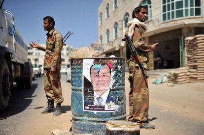 Varios soldados realizan un control a los veh&iacute;culos junto a un cartel electoral del &uacute;nico aspirante a las elecciones y vicepresidente yemen&iacute;, Abdo Rabo Mansur Hadi, en Sana, Yemen.