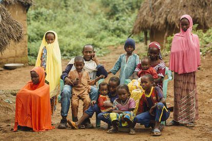Retrato de familia de Amina, que son de etnia peul y de origen centroafricano refugiados en Camerún antes de que Amina naciera. Los padres son Moussa (43 años) y Zeinabou (30 años). De izquierda a derecha, en la fila de abajo: Amina (13) con velo naranja; Idrissa (5) apoyado en su padre; Aissatou (2) en brazos de Ismaila (11). A su lado, con camiseta rosa está Hapsatou (7) y con camiseta del F.C. Barcelona, Moumini (8). En la fila de arriba: Nafisatou (10) con velo amarillo, Yaouba (6) con gorro azul; Mariama (18 meses) en brazos de su madre, y Aminatou (12) con velo rosa. Falta un varón más mayor que Amina, que se marchó de Yassa para buscar trabajo.