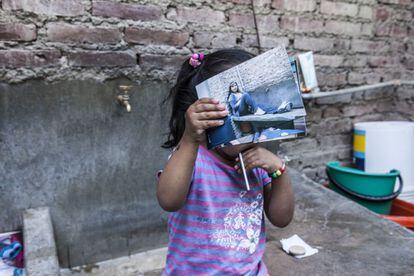 Una niña juega con las fotos de su madre en el patio de la cárcel San Pablo.