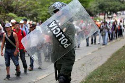 Un policía camina junto a varios campesinos que participan en una marcha en Cali (Colombia). EFE/Archivo