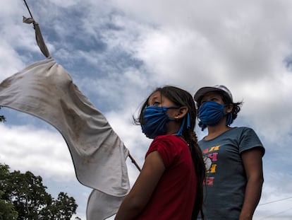 Una mujer y su hija se encuentran en una carretera con una bandera blanca improvisada pidiendo comida durante la cuarentena obligatoria decretada por el gobierno contra la propagación de la covid-19 en San Luis Talpa, El Salvador, el 29 de mayo de 2020.