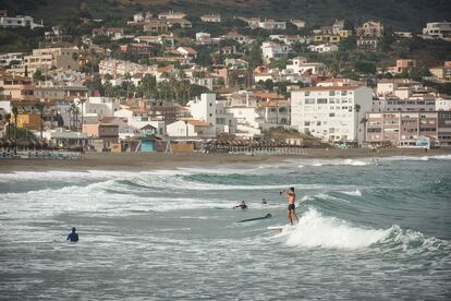 Several people surf and paddle surf on the beach of Puerto Deportivo de Sotogrande.