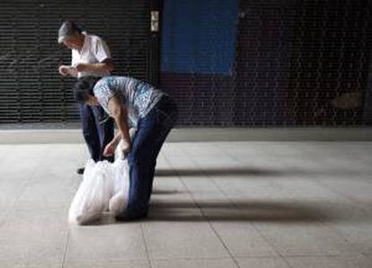 Una pareja revisa su compra a la salida de un supermercado en Caracas (Venezuela). EFE/Archivo