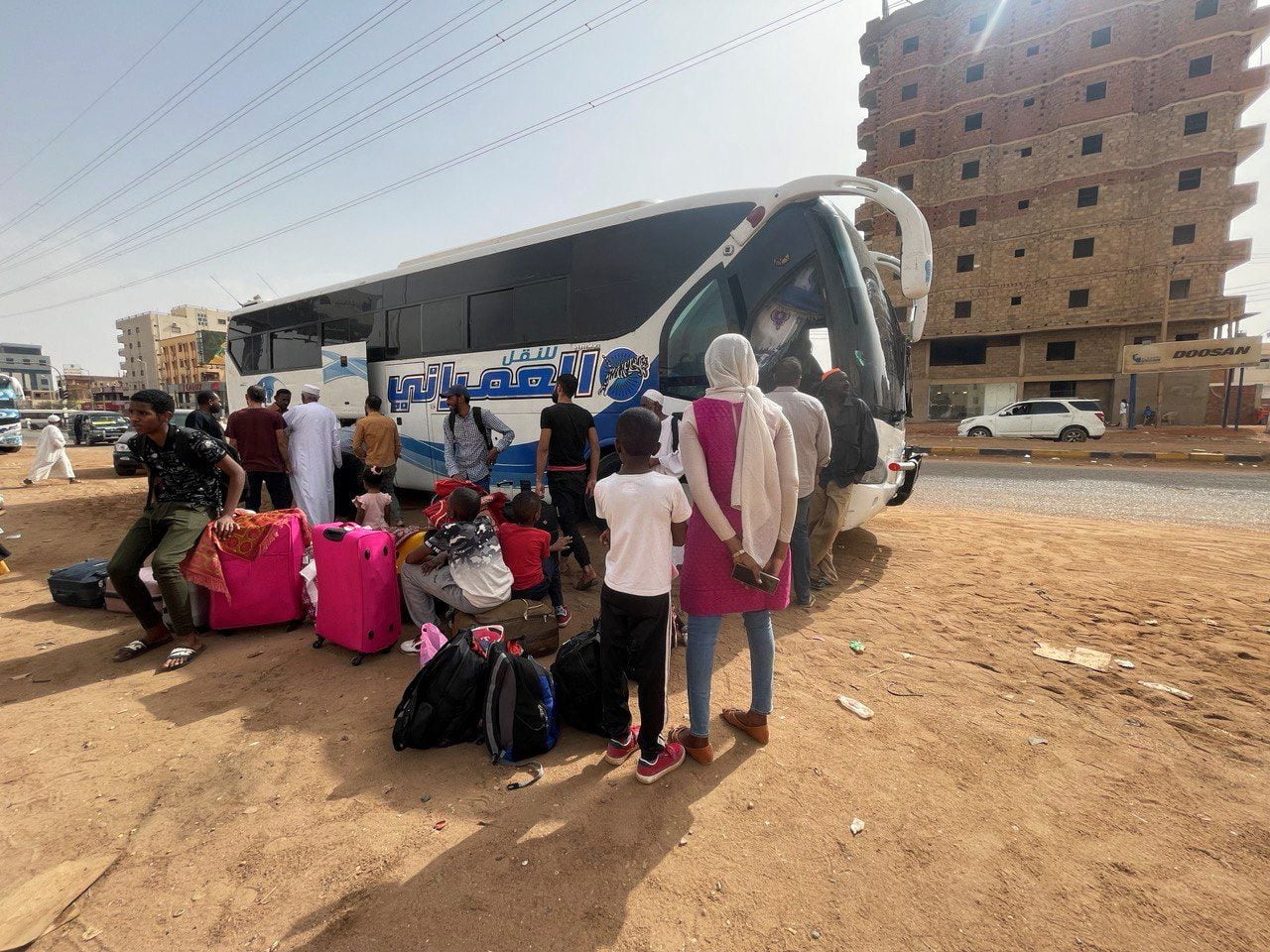 Un grupo de personas espera frente a un autobús para huir de los enfrentamientos entre el grupo paramilitar Fuerzas de Apoyo Rápido y el ejército, este lunes en Jartum.