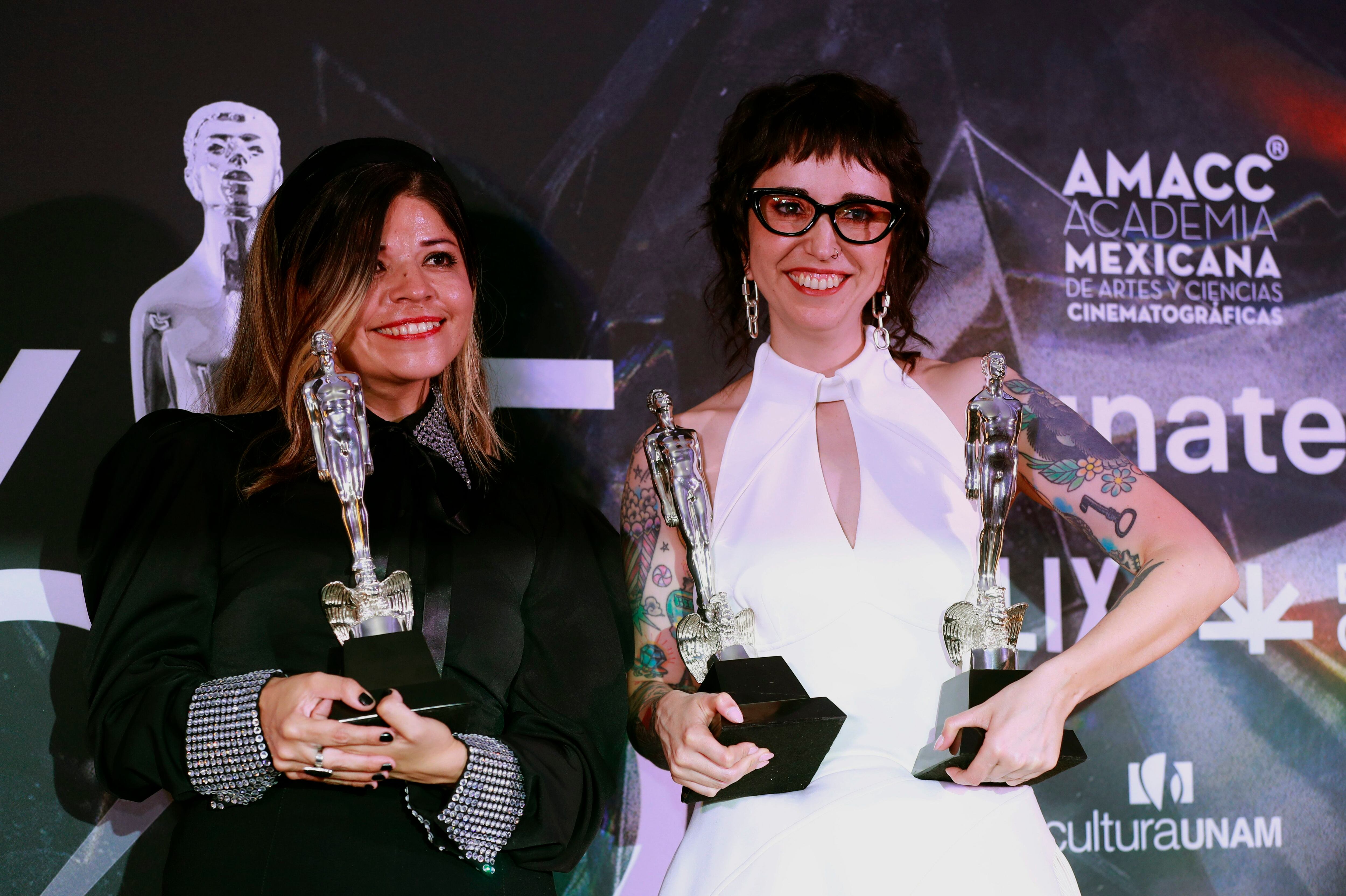 La guionista Abia Castillo (i) y la directora mexicana de cine, Michelle Garza Cervera posan con el premio Ariel por mejor guión original por 'Huesera'.
