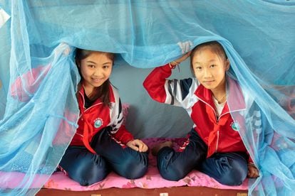 Dos estudiantes del internado Friendship Primary School, de la provincia china de Yunnan muestran las redes mosquiteras con las que se protegen del mosquito que transmite la malaria.