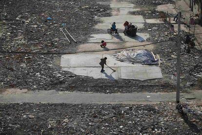 Un niño barre una zona llena de escombros donde serán construidos unos rascacielos en el centro de Shanghái (China).