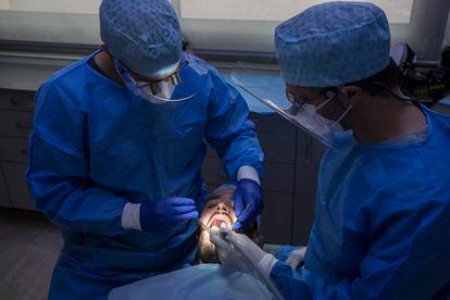 Dos profesionales atienden a un paciente en una clínica dental de Barcelona.