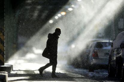 Un hombre camina bajo las vías del tren elevado en Filadelfia. Una tormenta invernal se extiende desde Kentucky a Nueva Inglaterra.