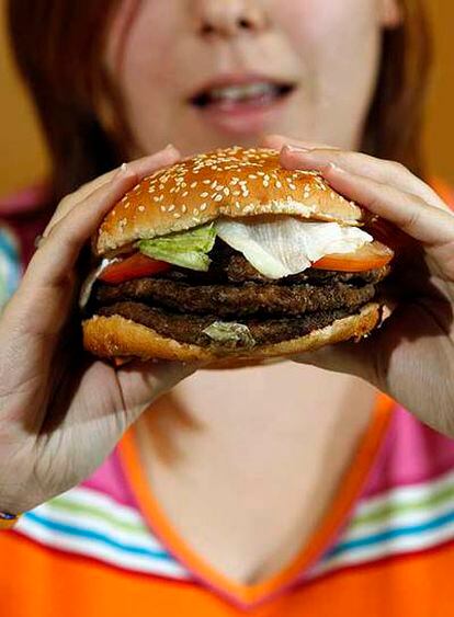 Una mujer come una hamburguesa de Burger King.
