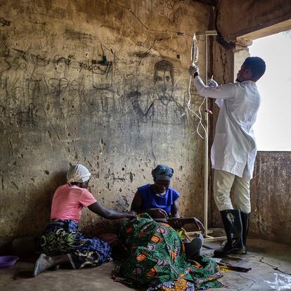 Emmanuel Chipokodzi, asistente médico del centro de salud de Mtosi, Malawi, revisa la medicación de una paciente de cólera mientras los familares de esta la apoyan.