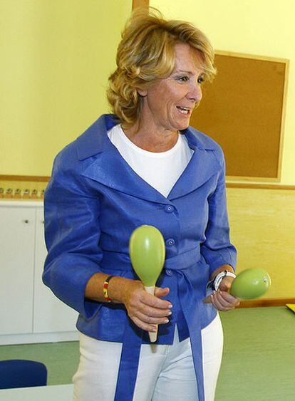 La presidenta de Madrid agita unas maracas durante la inauguración de una escuela infantil.