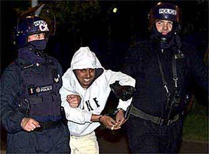 Dos policías llevan a un detenido tras los disturbios raciales en Manchester.