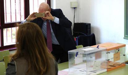 Un miembro de una mesa electoral hace una foto a través de su móvil en el instituto Conde de Orgaz en Madrid.