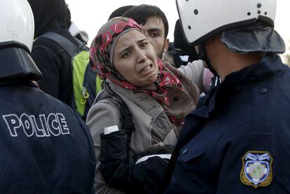 Una mujer siria con su bebé, llora frente a un cordón de policía mientras tratan de llegar a Macedonia.