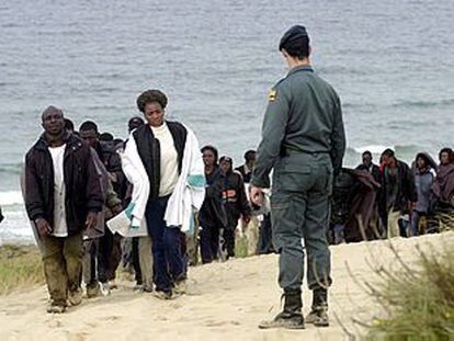 Uno de los grupos de inmigrantes camina vigilado por un agente de la Guardia Civil