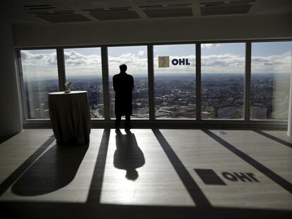 Un hombre mirando por una ventana del edificio de OHL en Madrid