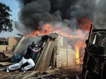 Un surafricano trata de quemar una chabola en un asentamiento de Johanesburgo.