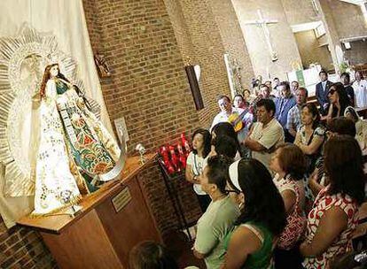 Inmigrantes peruanos rezan ante la Virgen de la Puerta en una iglesia del distrito de Latina.